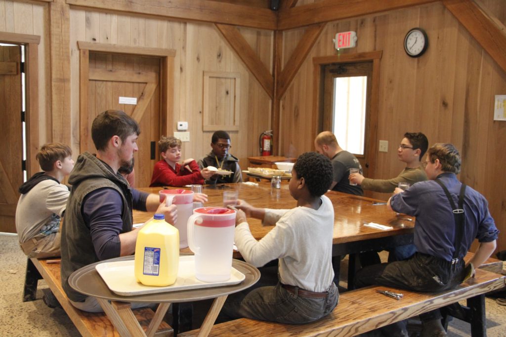 group of boys and chiefs sitting around table at mealtime